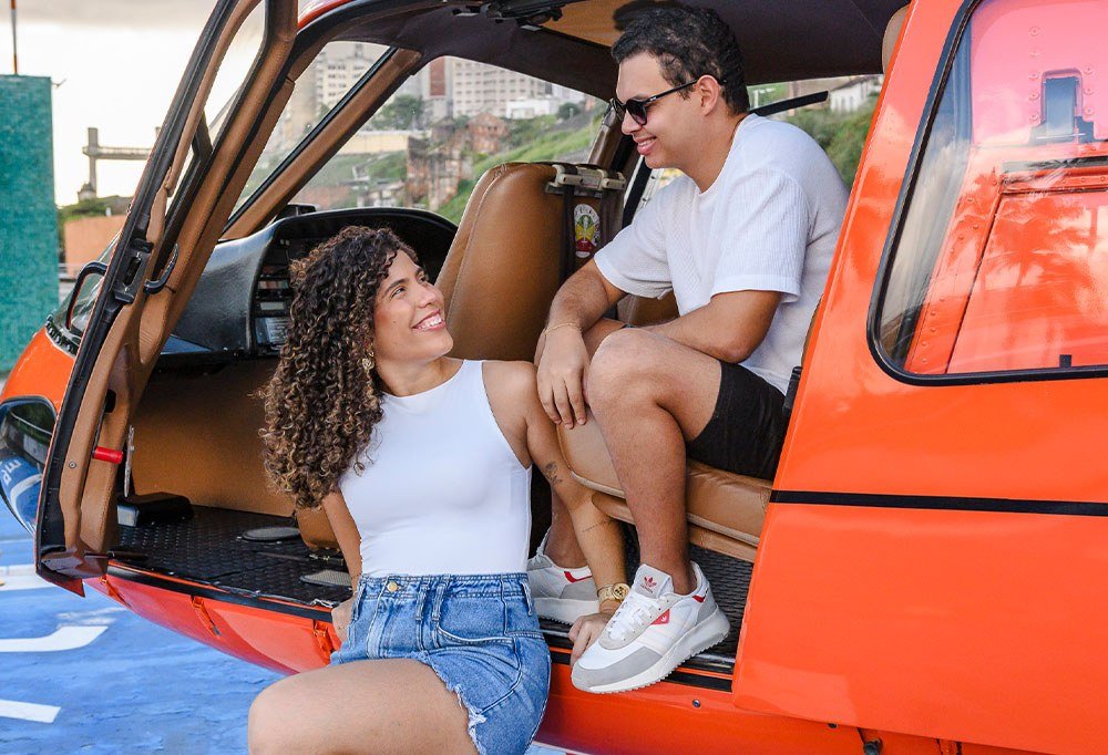 Casal se preparando para embarcar no helicóptero laranja da HELIX
