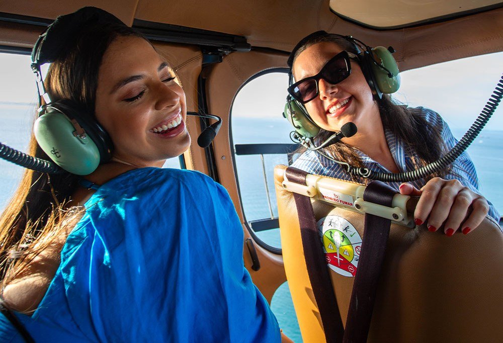 Duas passageiras sorrindo durante a experiência aérea da HELIX